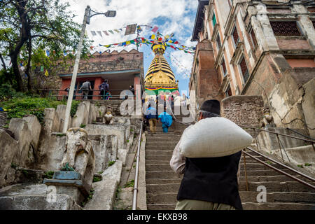 An old nepali man carrying a bag is going up the stairs of Swayambhunath Monkey temple in Kathmandu, Nepal Stock Photo