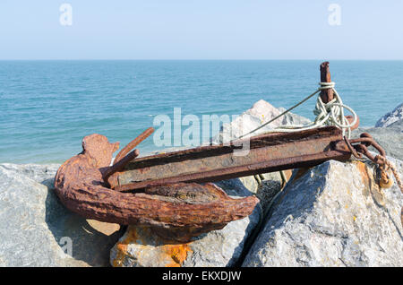 Old rusty anchor sitting on rocks at Beesands in Devon Stock Photo