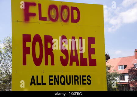 For sale sign on land next to a river which floods in a residential area. Stock Photo