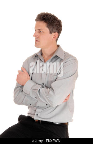 A young businessman sitting isolated for white background with his hands  grossed over his chest, in a grey shirt. Stock Photo