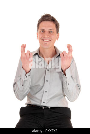 A happy smiling young man in a grey shirt, holding up his hands and  crossing his fingers, Isolated for white background. Stock Photo