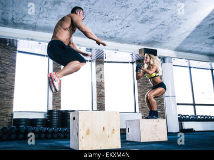 Man and woman jumping on fit box at gym Stock Photo