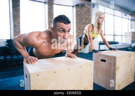Woman and man doing push ups on fit box at gym Stock Photo