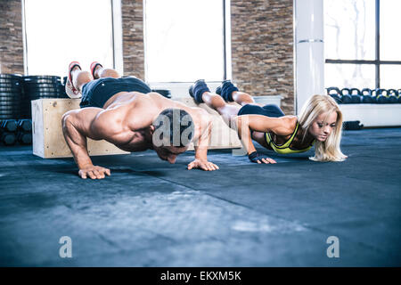 Woman and man doing push ups at gym Stock Photo
