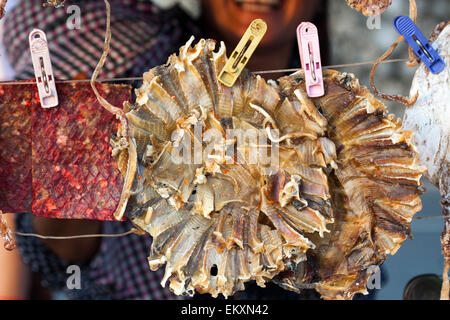 A woman selling dried fish on the street in Asia. Stock Photo