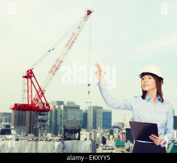 smiling businesswoman in helmet with clipboard Stock Photo