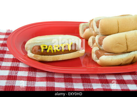 Party hot dog on red platter with stack of hot dogs on buns. Stock Photo