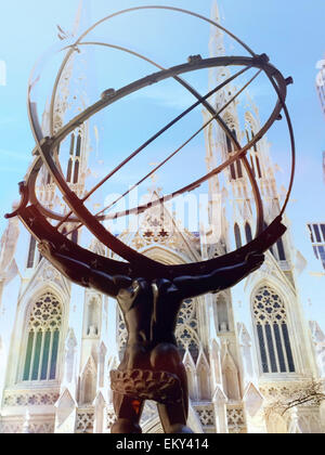 Ancient Greek Titan Atlas Holding the Heavens Bronze Armillary Sphere Sculpture in Rockefeller Center with St. Patrick's Cathedral in the Background, NYC, USA Stock Photo