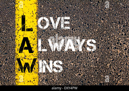 Love Always Wins - LAW Concept. Conceptual image with yellow paint line on the road over asphalt stone background. Stock Photo
