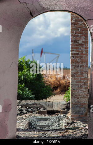 Oil well and fracking site through doorway of abandoned home in Shafter. Kern County, located over the Monterey Shale, has seen Stock Photo