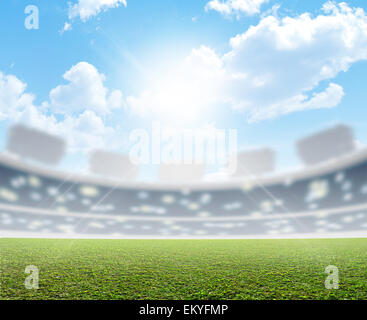 A generic sports  stadium with a marked green grass pitch in the daytime under a blue sky Stock Photo