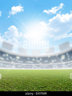 A generic sports  stadium with a marked green grass pitch in the daytime under a blue sky Stock Photo