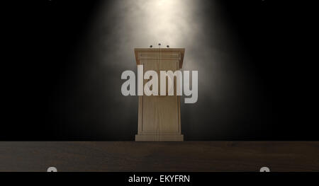 A wooden speech podium with three small microphones attached on a dark background spotlit by a single spotlight Stock Photo