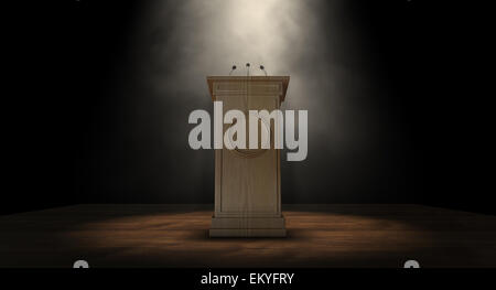 A wooden speech podium with three small microphones attached on a dark background spotlit by a single spotlight Stock Photo