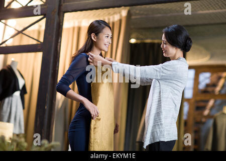 Clothing store owner helping customer with choosing dress Stock Photo