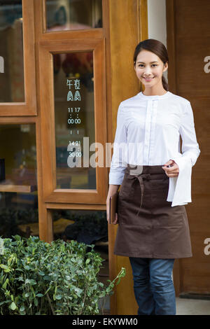 Young waitress standing in restaurant doorway Stock Photo