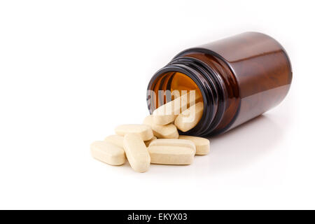 Vitamin pills fallen out of brown bottle. Studio shot on white background, view side of bottle. Stock Photo