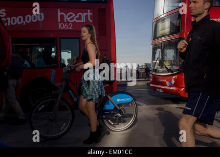 Girl cyclist on a Barlcays-sponsored Boris bike, crosses  southbound over London Bridge during the evening rush hour. Stock Photo