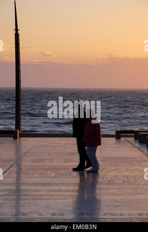 Couple walking along the promenade as the sun is setting at the holiday resort of Blackpool on the Fylde Coast Stock Photo