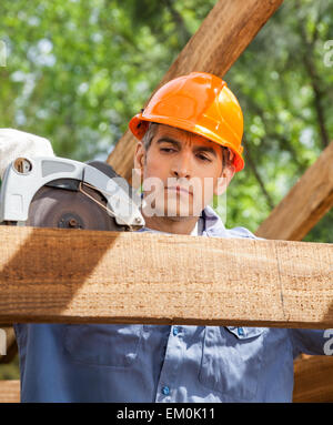 Construction Worker Using Electric Saw On Timber Frame Stock Photo