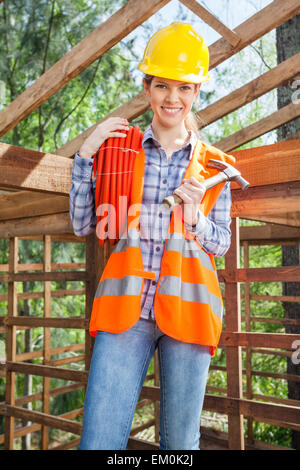 Female Worker Holding Pipe And Hammer At Site Stock Photo