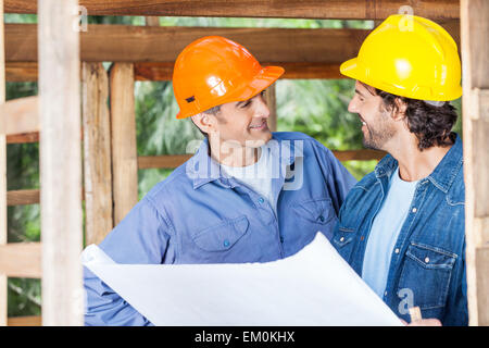 Smiling Architects Discussing Over Blueprint At Site Stock Photo