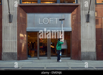 A workman cleaning the exterior of the of the Loft, a women's clothing store on Broadway in Greenwich Village, New York City. Stock Photo