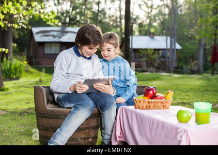 Smiling Siblings Using Tablet Computer At Campsite Stock Photo