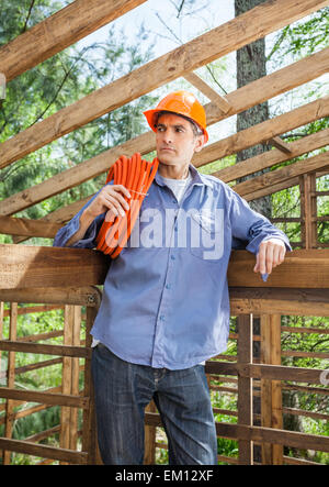 Thoughtful Construction Worker Carrying Rolled Pipe Stock Photo