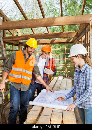 Engineers Working On Blueprint In Incomplete Wooden Cabin Stock Photo