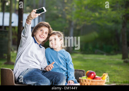 Siblings Taking Selfportrait Through Smartphone At Campsite Stock Photo