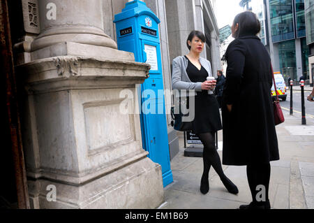 London, England, UK. Woman with a coffee, talking and standing by a police call box. Stock Photo