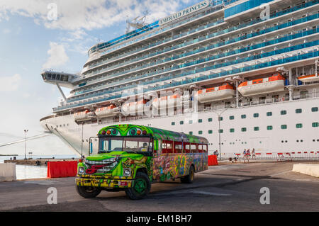 A Princess Cruise Line cruise ship, Emerald Princess, docked in Oranjestad. A colorful tour bus waiting for the tourists. Stock Photo