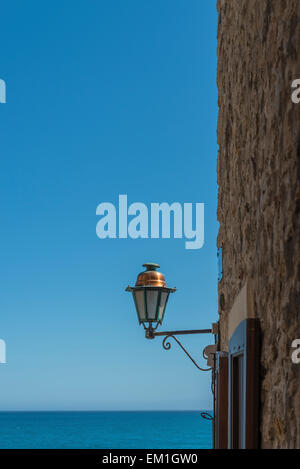 Traditional streetlight in Antibes old town with a view out to the azure blue Mediterranean sea Stock Photo