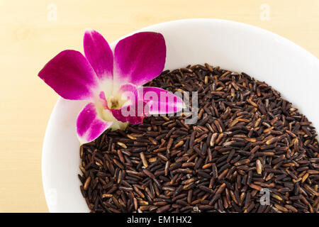 Thai Brown Rice Berry in White Bowl with Orchid Stock Photo