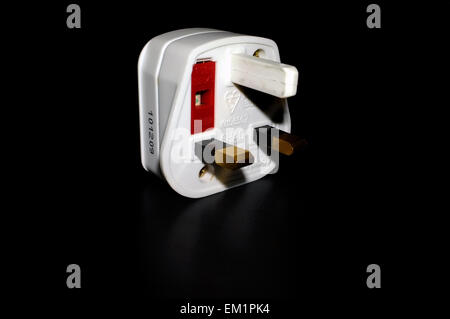 A British three pin plug adapter photographed against a black background. Stock Photo