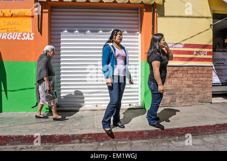 dignified old indigenous Mexican Indian woman is a contrast with 2 Indian teens wearing tight jeans San Cristobal de las Casas Stock Photo