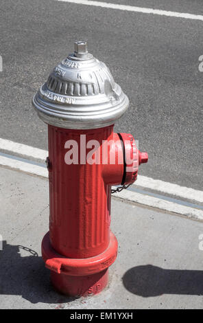 A red painted fire hydrant on the sidewalk on a street in New York City Stock Photo