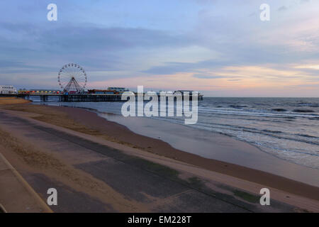 blackpools central pier in the distance from the promenade showing the sea and big wheel on the pier with subdued evening light Stock Photo