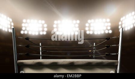 An old vintage boxing ring surrounded by ropes spotlit by floodlights in an arena setting at night Stock Photo