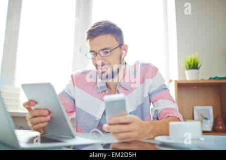 Modern young man using smartphone and touchpad Stock Photo