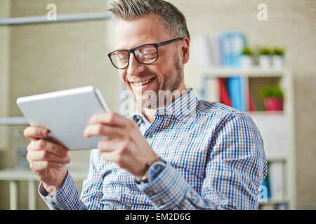 Happy man in eyeglasses using digital tablet Stock Photo