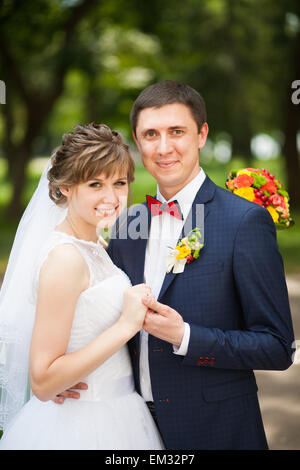 happy bride, groom standing in green park, look at camera. lovers in wedding day. happy young couple in love. Stock Photo