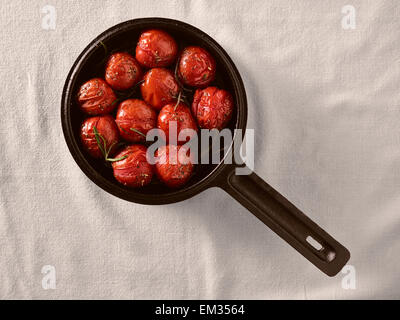 Grilled cherry tomatoes in a small cast iron pot, rosemary Stock Photo