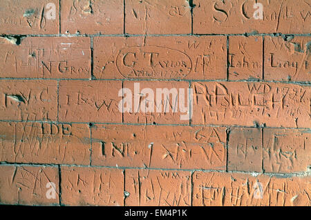 Brick Wall with carved signs and words Stock Photo