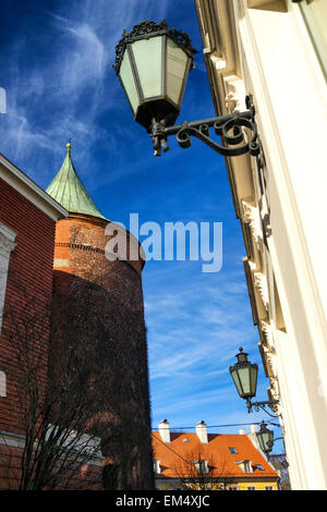 Ancient buildings and Powder Tower with lights on the facades on the background of blue sky with clouds in Riga in early spring. Stock Photo