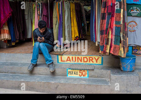 Nepali seller texting on his cell phone Stock Photo