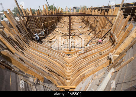 Building a traditional wooden dhow cargo ship in shipyard beside The Creek River in Dubai United Arab Emirates Stock Photo