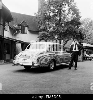 The chauffeur of The Beatles singer John Lennon standing beside Lennon's Rolls Royce with its decorative detailing. Stock Photo