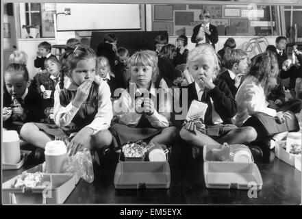 Children of Holy Trinity Primary School in Lewisham can not have school dinners as there is nowhere to serve them. Instead they must bring packed lunches and eat them on the school floor. 15th October 1991. Stock Photo
